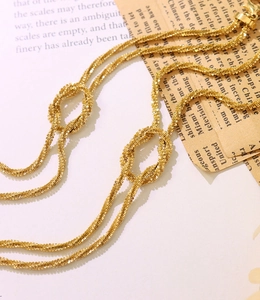 Detailed macro of gold twisted rope chain bracelet with knot design and lobster clasp
