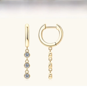 Detailed shot of gold hoop earrings featuring three sparkling round moissanite tassels