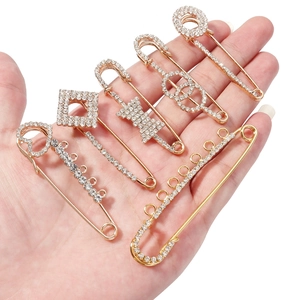 Golden safety pin brooch set with white crystals in heart and bow shapes for scarves