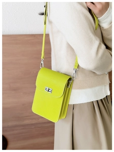 Detail of lime green textured crossbody bag with silver clasp worn by a model