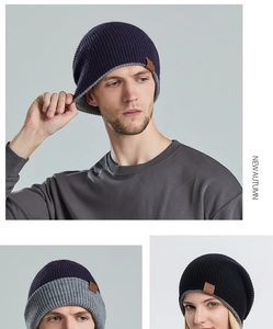 Detail of navy and light grey knitted beanie with brown leather logo patch on side