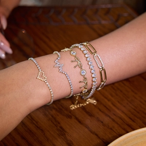 Set of gold titanium steel bracelets with heart and zircon charms on model's wrist