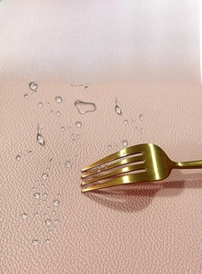 Detail of pink PU leather placemat showing waterproof surface and gold fork accessory