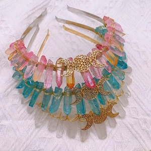 Three crystal headbands in pink, blue, and clear with gold moon decor on a white fabric