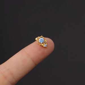 Goldener Edelstahl-Ohrstecker mit blauem Zirkonia, präsentiert auf dem Finger