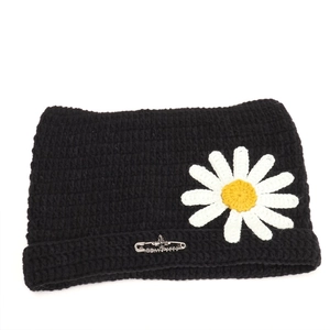 Detailed view of black cat ear beanie featuring a daisy patch and silver cross pin accessory
