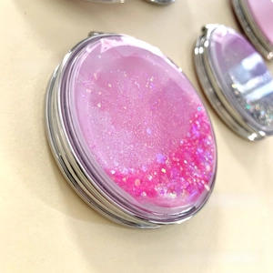 Close-up of pink quicksand folding compact mirror with glitter and star sequins