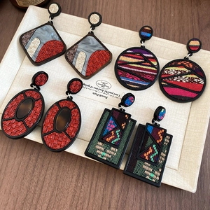Detail view of geometric bohemian drop earrings with woven fabric and resin inlays