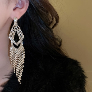Close-up of elegant gold tassel earrings with shimmering rhinestones on a model