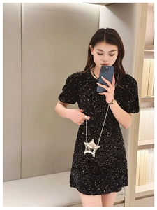 Close-up of a silver star-shaped mini crossbody bag styled with a black sequin dress