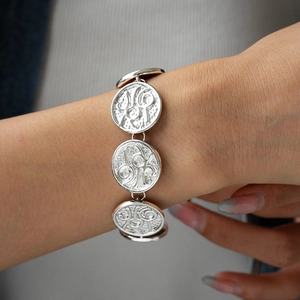 Close-up of vintage silver bracelet featuring circular coin pendants with embossed texture