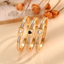 Detail of three gold titanium steel heart bangles set with sparkling zircon crystals