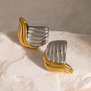 Detail of two-tone gold and silver stainless steel earrings on a textured stone base