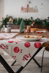 Detail of Christmas table mat with red holiday ornaments and festive linen texture