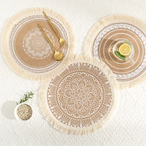 Close-up of round jute placemats with white mandala patterns and fringe tassels