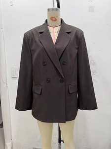 Détail d'un blazer marron foncé à double boutonnage, coupe oversize avec épaulettes et poches