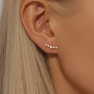 Close-up of gold stud earrings with white pearls and sparkling marquise crystals on model