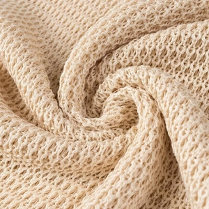 Gros plan sur le tissu tricoté beige montrant la maille complexe et le design ajouré