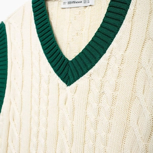 Chic cream cable knit V-neck vest with green contrast trim for a classic preppy style