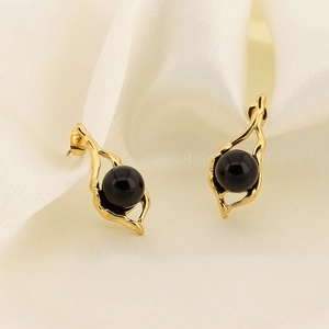 Detail of vintage gold stainless steel earrings with elegant black round gemstone