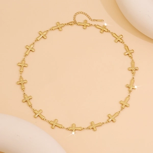 Golden stainless steel cross link chain necklace displayed on minimalist stone props
