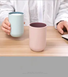 Close-up of minimalist pastel pink and blue mouthwash cups held in hands