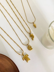 Detail of four golden marine life pendants with sea turtle and dolphin on bead chains