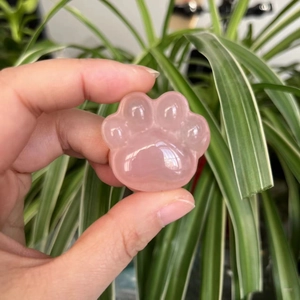Polished pink rose quartz crystal in cute cat paw shape carving held for scale