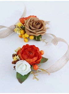 Close-up of handmade wedding corsage with orange peonies, brown roses, and rustic ribbon