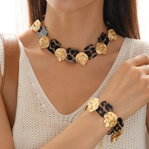 Close-up of leopard resin necklace and gold geometric accents worn by a model