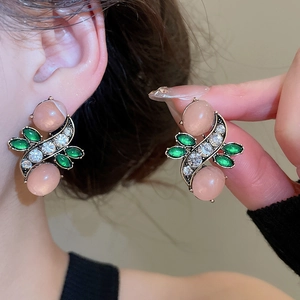 Detail of pink cat-eye stone and green gem earrings with bronze floral setting