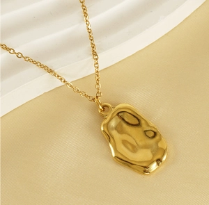 Macro view of gold stainless steel necklace featuring irregular hammered lava texture pendant