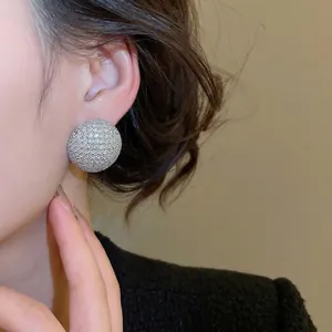 Boucles d'oreilles argentées étincelantes avec cristaux pavés ronds sur un modèle