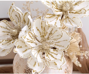 Close-up of artificial white magnolia with gold glitter edges in a ceramic vase