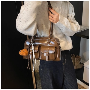 Close-up of a vintage brown pillow bag with two front pockets worn by a model