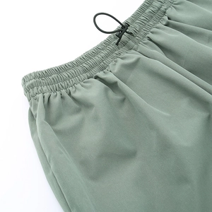 Dettaglio dei pantaloni cargo verdi con vita elastica e fibbia con coulisse regolabile