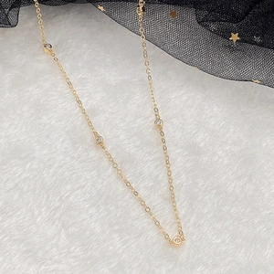 Detailed macro view of thin gold choker chain with five round bezel-set zircon stones