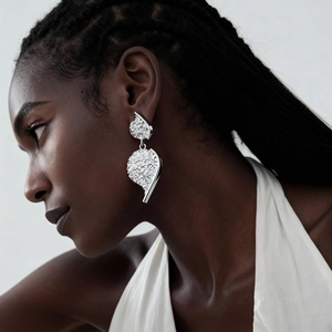 Close-up of metallic textured silver earrings with unique leaf design on model's ear