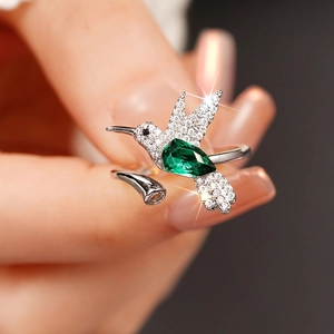 Detailopname van een kolibri-ring met een peer-vormige smaragdgroene edelsteen