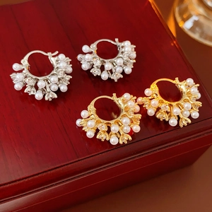 Detail of vintage U-shaped pearl earrings with cubic zirconia on a dark red box
