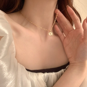 Close-up of a gold-plated flower mother-of-pearl disc necklace worn by a female model