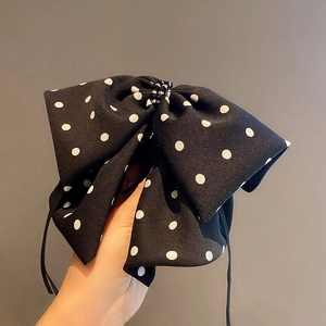 Macro detail of a black bow hair clip with white polka dots and black bead accents