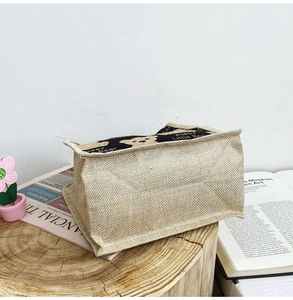 Close-up of burlap lunch bag with cute bear pattern on a rustic wooden stand