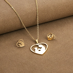 Detailed close-up of golden heart-shaped necklace and earrings set with mother-child silhouette