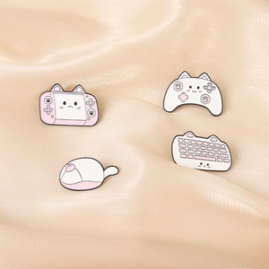 Cute pink and white cat-themed enamel pins featuring game console, mouse, and keyboard