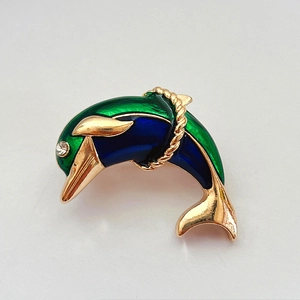 Detail of dolphin brooch with green and blue enamel on a gold-plated metal base