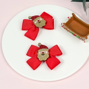 Detail of red Christmas hair bows with glittery Santa Claus centers on a white tray