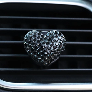 Detail view of heart-shaped car air vent clip covered in glossy black rhinestones