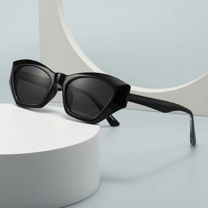 Occhiali da sole geometrici cat-eye neri con lenti grigio scuro su supporto bianco