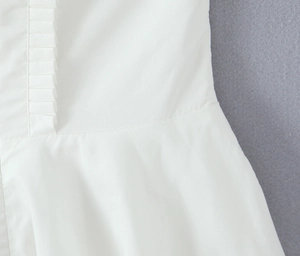 Macro detail of vertical pleats and waist seam on elegant white halter dress